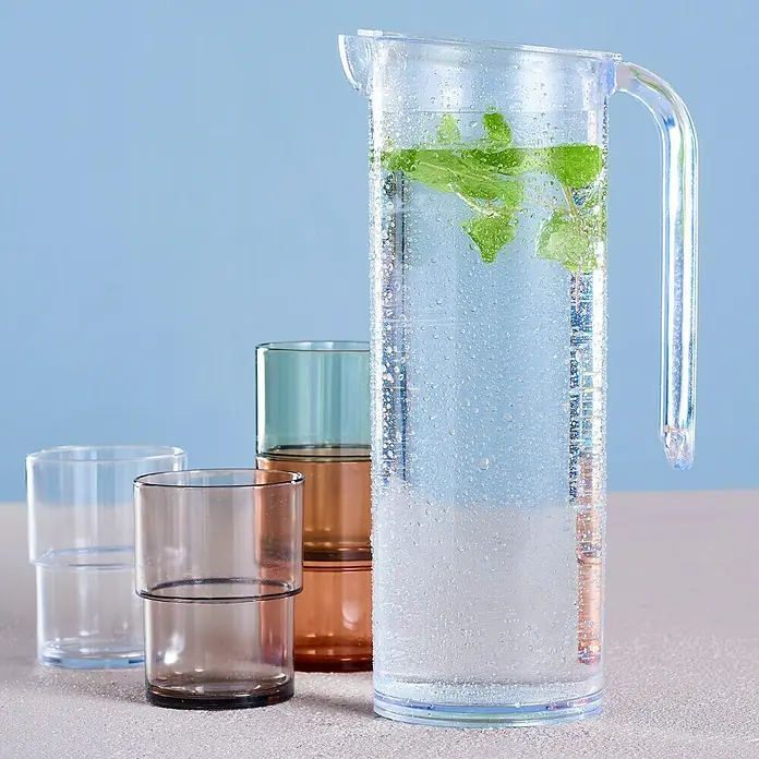 Jarra con vasos - Capacidad volumétrica: 1 l, Plástico - Jarra de vidrio transparente con agua y menta, junto a vasos apilados de colores. Práctico y elegante para el uso diario.