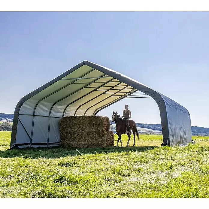 ShelterLogic Garage - 730 x 680 x 380 cm, Stahl - Großes grau-weißes Stoffzelt, das ein Pferd und Heuballen auf einer Wiese beherbergt.
