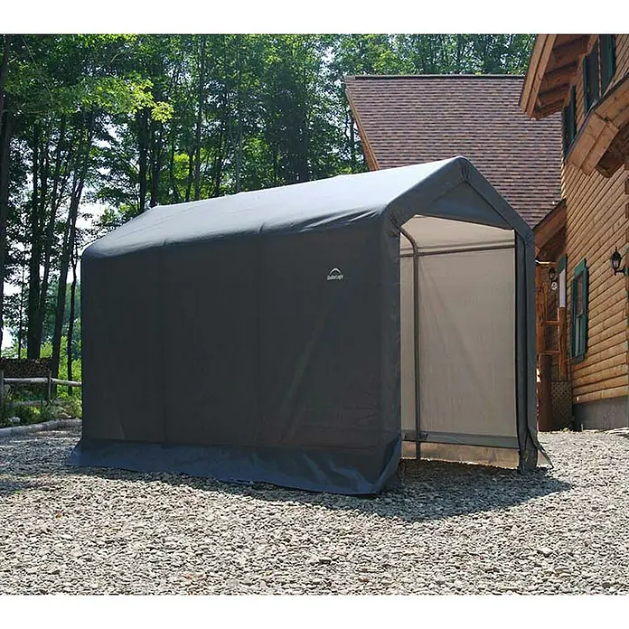 ShelterLogic Gerätehaus - Außenbreite inkl. Dachüberstand: 180 cm, Außentiefe inkl. Dachüberstand: 300 cm, Stahl, Grau - Bild eines tragbaren Unterstandes aus grauem Stoff mit weißer Innenseite. Er steht auf einem Schotterplatz neben einem Holzhaus.
