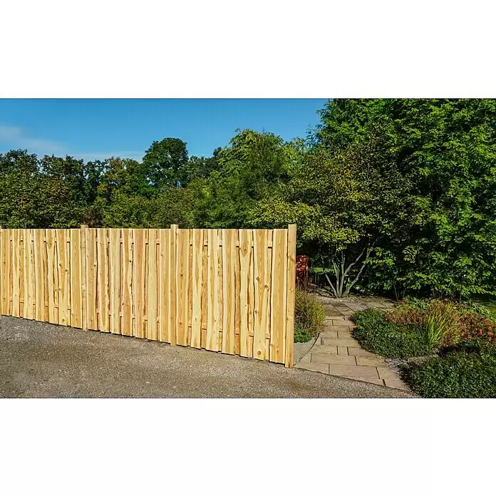 Joda Sichtschutzelement Ponderosa - 180 x 180 cm, Holz, Natur - Heller Holzzaun trennt einen Kiesweg von einem üppigen Garten mit grüner Bepflanzung und einem Steinweg.