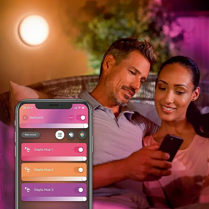 Philips Hue LED-Außenwandleuchte White & Color Ambiance Daylo - 15 W, 22 x 22 x 7,6 cm, Silber, IP44 - Ein Paar entspannt sich und steuert die Daylo Hue Beleuchtung mit einer App auf ihrem Smartphone.