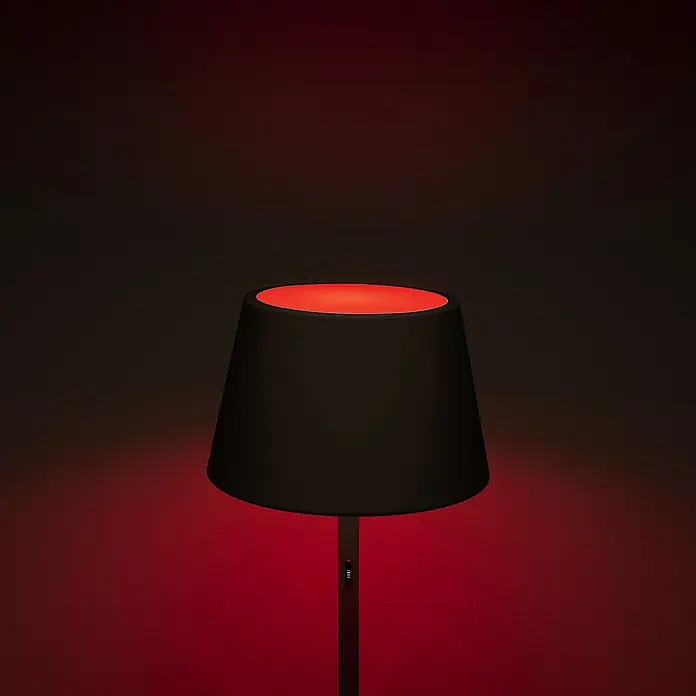 Konstsmide Außenleuchte Pomezia - Akkubetrieben, 10 W, RGBW, 35 x 35 x 150 cm, Mit Leuchtmittel, Schwarz - Nahaufnahme einer modernen Stehlampe mit schwarzem Schirm und rotem Licht, die ein gemütliches Ambiente erzeugt.
