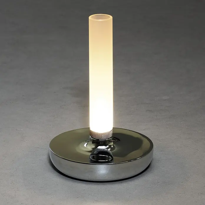 Konstsmide Akku-Tischleuchte Biarritz - 2,5 W, L x B x H: 13,5 x 13,5 x 20,5 cm, Silber, Warmweiß - Nahaufnahme einer eleganten, modernen Tischleuchte mit einem zylindrischen Lampenschirm und einem glänzenden Metallsockel.