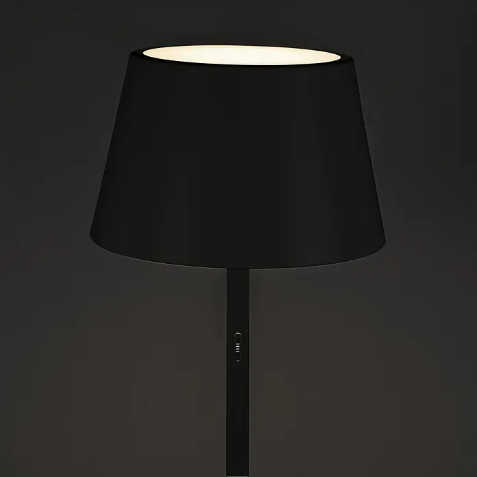 Konstsmide Außenleuchte Pomezia - Akkubetrieben, 10 W, RGBW, 35 x 35 x 150 cm, Mit Leuchtmittel, Schwarz - Nahaufnahme einer stilvollen, schwarzen Tischleuchte mit einem warmen Lichtschein, die eine elegante Atmosphäre schafft.