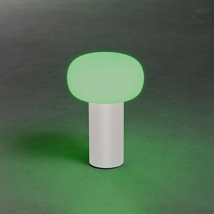 Konstsmide Akku-Tischleuchte Antibes - 2,5 W, L x B x H: 13 x 13 x 19 cm, Weiß, Mehrfarbig - Nahaufnahme einer modernen Pilzlampe mit grünem Schirm und weißem Sockel auf einer grünen Oberfläche.