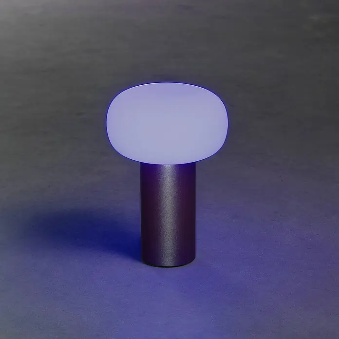 Konstsmide Akku-Tischleuchte Antibes - 2,5 W, L x B x H: 13 x 13 x 19 cm, Rost, Mehrfarbig - Nahaufnahme einer modernen violetten Tischleuchte mit zylindrischem Sockel und kugelförmigem Lampenschirm, die ein sanftes Licht ausstrahlt.