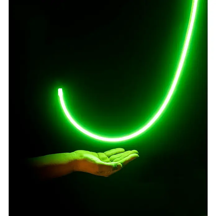 Alverlamp Tira LED a metros Neon - Largo: 100 m, Color de luz: Verde, 9 W, 1.308 lm - Tubo de neón verde sobre una mano, que parece flotar mágicamente en la oscuridad. El producto es ideal para la decoración moderna.