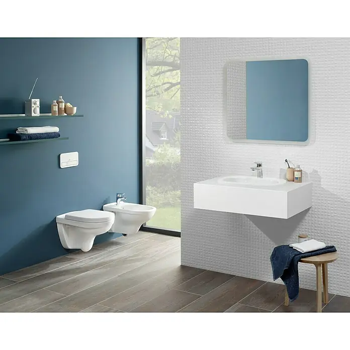 Villeroy & Boch Wand-WC-Set Targa StyleSpülrandlos, Ohne Spezialglasur, Spülform: Tief, WC Abgang: Waagerecht, Weiß - Ein modernes Badezimmer mit einer wandhängenden Toilette, Bidet, Waschbecken und einem Spiegel, die ein elegantes und minimalistisches Design zeigen.