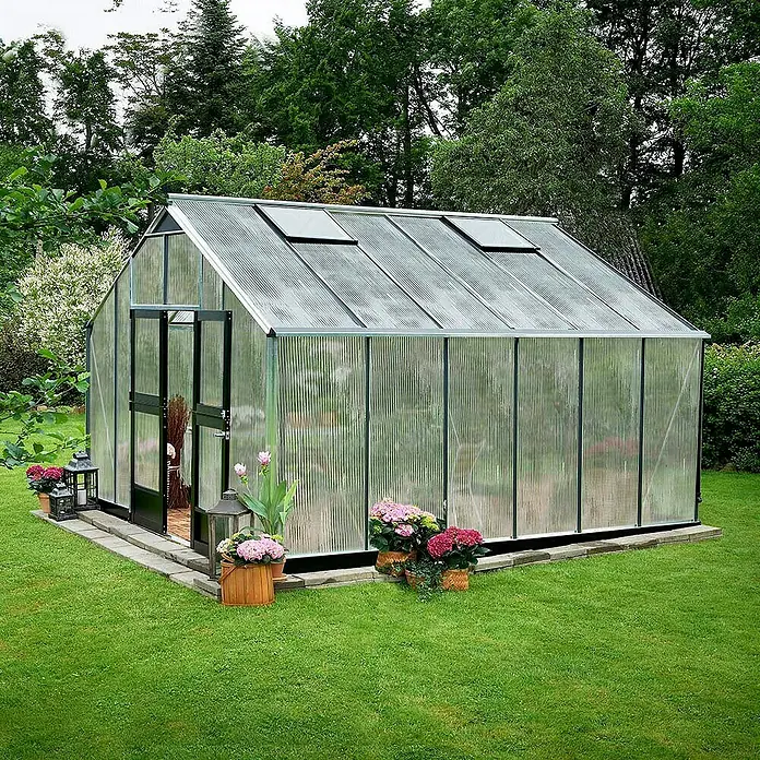 Juliana Gewächshaus Gärtner - Außenmaß inkl. Dachüberstand (B x T): 368 x 439 cm, Material Seitenwand: Kunststoff, 10 mm, Silber/Schwarz - Ein Gewächshaus mit Blumenbeeten steht im Grünen. Das Glasgewächshaus ist mit Dachfenstern ausgestattet.
