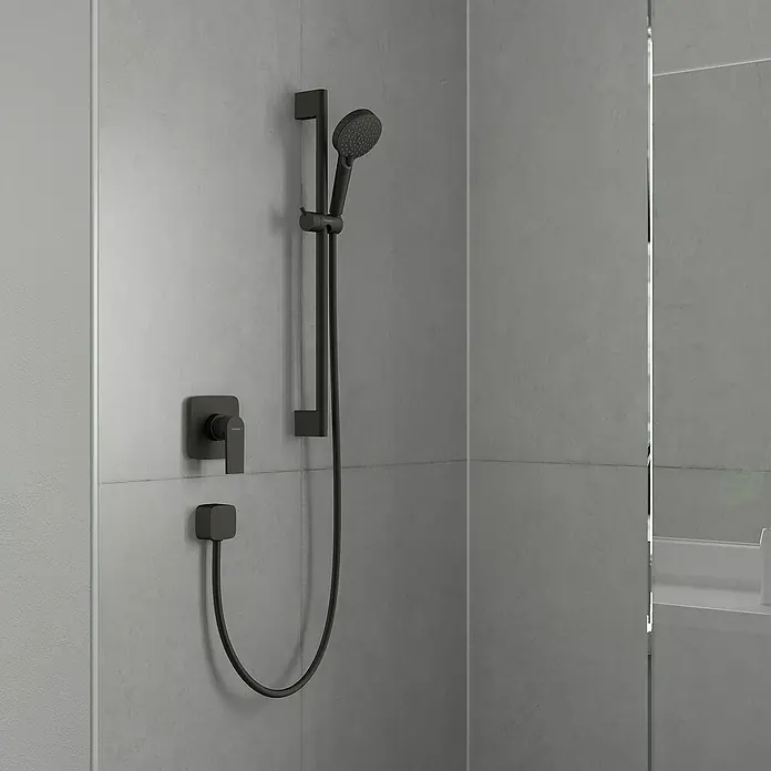 Hansgrohe Vernis Shape UP-Brausearmatur - Schwarz, Matt - Duscharmatur mit Stabhandbrause und quadratischem Bedienfeld in dunkler Ausführung vor grauer Wand.