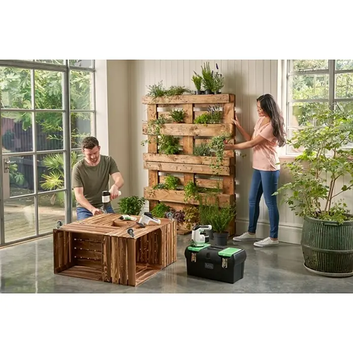Black+Decker reviva Caja para herramientas - 19'', Polipropileno - La imagen muestra un proyecto de jardinería DIY con una jardinera de palets y una mesa de cajas de madera, ideal para jardineros de interior.