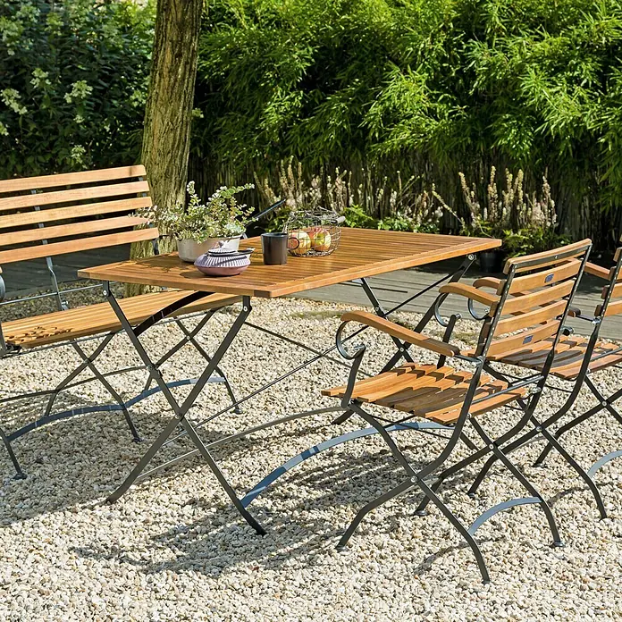 Sunfun Moni Klappbank - B x T x H: 120 x 57 x 90 cm, Akazie, Naturbraun/Schwarz, Klappbar - Gartenmöbelset mit Holztisch und Stühlen auf Kies. Ideal für den Außenbereich, um entspannte Stunden im Garten zu verbringen.