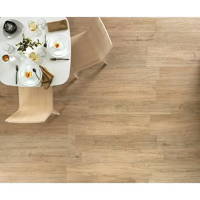 Harmonie by Palazzo Feinsteinzeugfliese - 30 x 120 cm, Eiche Hell, Matt - Helles Interieur mit Holzboden in Dielenoptik, gedecktem Esstisch und hellen Holzstühlen. Der Boden verleiht dem Raum Wärme und Eleganz.