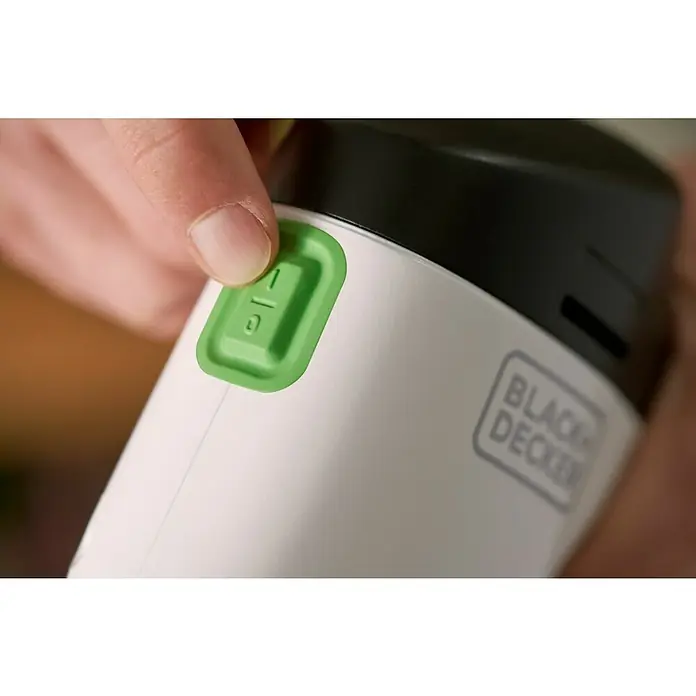 Black+Decker reviva Lijadora delta de batería - 12 V, 1,5 Ah, 11.000 r.p.m. - Primer plano de un electrodoméstico de cocina Black+Decker con un dedo presionando un botón verde con símbolos, centrado en la funcionalidad.