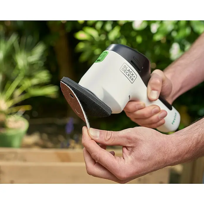 Black+Decker reviva Lijadora delta de batería - 12 V, 1,5 Ah, 11.000 r.p.m. - Primer plano de un dispositivo Black+Decker Reviva que quita pelusa y pelusas de una prenda de vestir.
