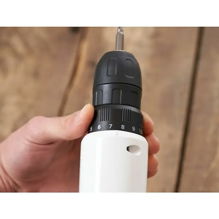 Black+Decker reviva Taladro atornillador de batería - 12 V, 1 batería, 1,5 Ah, 26 Nm - Primer plano de una mano sosteniendo un taladro inalámbrico blanco, ajustando el anillo de torque al nivel 6, ideal para atornillar con precisión.