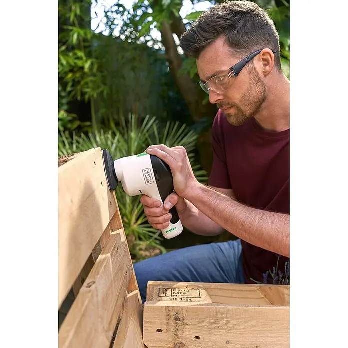Black+Decker reviva Lijadora delta de batería - 12 V, 1,5 Ah, 11.000 r.p.m. - Un hombre lija madera con una lijadora Black+Decker Reviva. La lijadora de mano es ideal para superficies de madera.