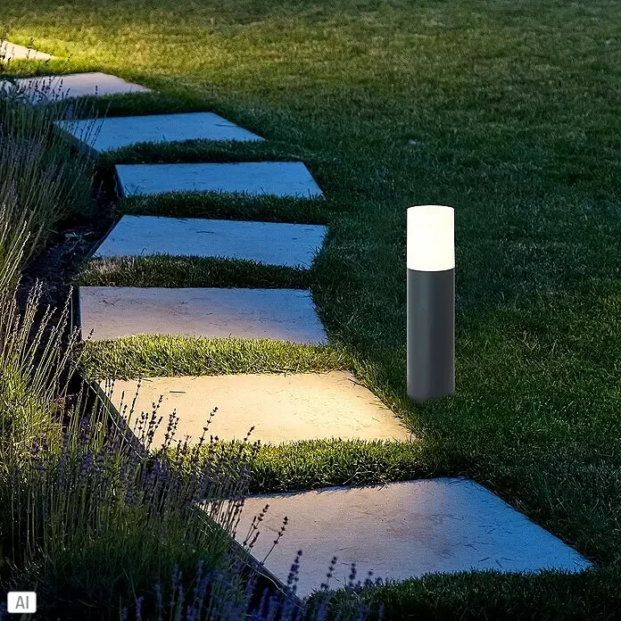 Brilliant Außensockelleuchte - 28 W, Farbe Gehäuse: Anthrazit, Ohne Leuchtmittel - Zylindrische Außenleuchte in Dunkelgrau und Weiß beleuchtet nachts einen Gartenweg aus Trittsteinen.