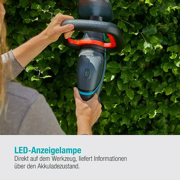 Gardena Power for All 18V Akku-Heckenschere ComfortCut 50 - 18 V, Li-Ionen, 1 Akku, Schwertlänge: 50 cm - Nahaufnahme einer GARDENA Akku-Heckenschere, die von einer Person vor einer grünen Hecke gehalten wird.