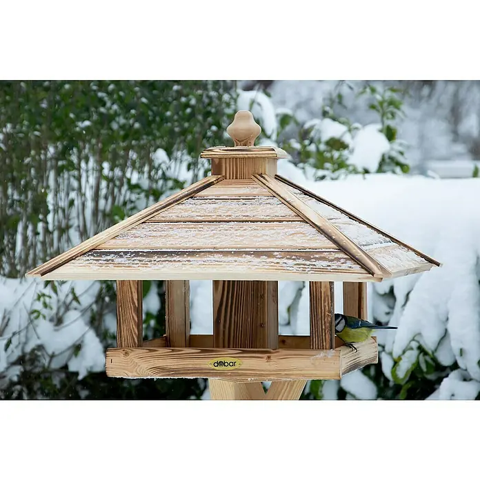 Dobar Vogelfutterhaus Lumbre - L x B x H: 50 x 50 x 36 cm, Braun, Holz - Ein hölzernes Vogelhaus mit einem kleinen Vogel darauf, umgeben von einer verschneiten Landschaft.