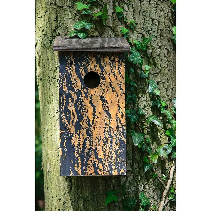 Dobar Nistkasten - L x B x H: 15,5 x 14,5 x 30 cm, Braun, Holz - Ein rechteckiges Vogelhaus aus Holz mit einem kreisförmigen Eingang, befestigt an einem Baumstamm, umrankt von Efeu.