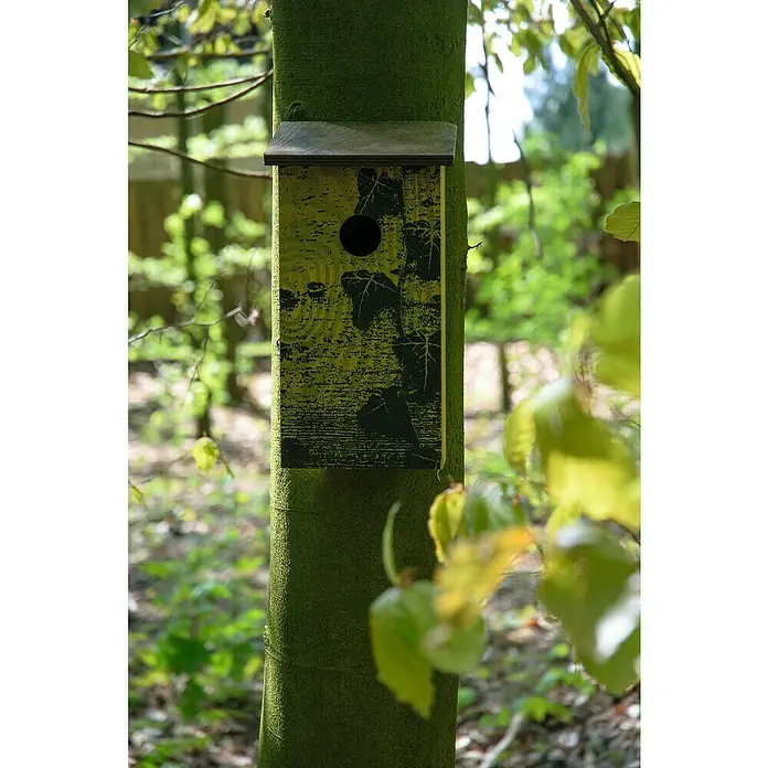 Dobar Nistkasten Fagus sylvatica - 15,5 x 14,5 x 30 cm, Braun, Holz - Ein Vogelhaus mit Blattmuster hängt an einem Baumstamm im Wald. Das hölzerne Vogelhaus bietet einen sicheren Nistplatz.