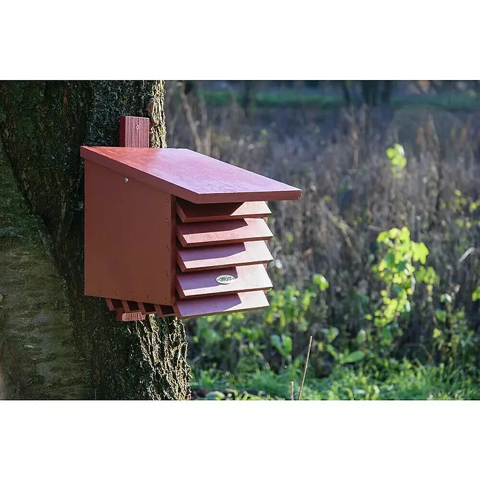 Dobar Insektenhotel für Florfliegen - 27 x 29 x 30 cm, Holz, Rot - Nahaufnahme eines braunen Fledermauskastens, der an einem Baum befestigt ist, mit einem schrägen Dach und mehreren horizontalen Schlitzen für den Ein- und Ausstieg.