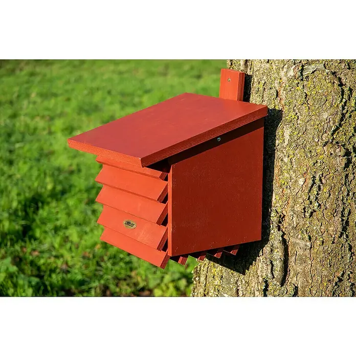 Dobar Insektenhotel für Florfliegen - 27 x 29 x 30 cm, Holz, Rot - Das Bild zeigt ein rotes Fledermaushaus, das an einem Baum befestigt ist. Das Haus ist aus Holz gefertigt und hat ein schräges Dach.