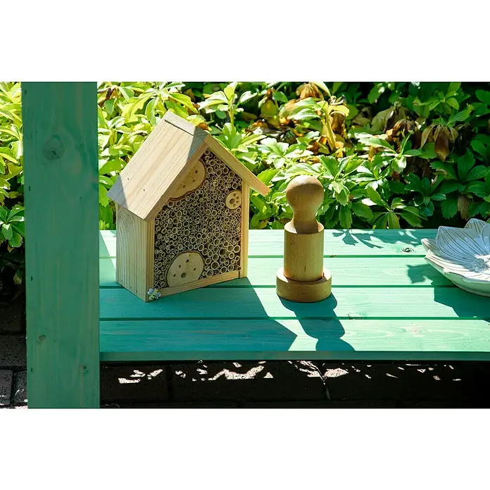 Dobar Hochbeet - L x B x H: 80,3 x 40 x 78,4 cm, Holz, Mintgrün - Ein hölzernes Insektenhotel und ein hölzerner Stempel sitzen auf einer mintgrünen Bank im Freien, umgeben von üppigem Grün.