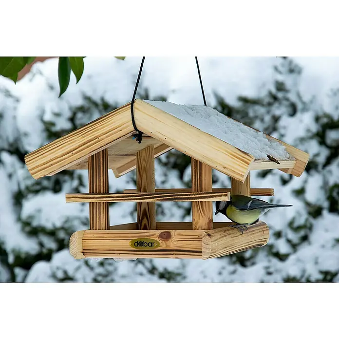 Dobar Vogelfutterhaus Quemado - L x B x H: 30 x 34,5 x 22,5 cm, Braun, Holz - Eine hölzerne Futterstelle mit Schnee auf dem Dach, an der ein Vogel sitzt. Ideal für die Fütterung von Wildvögeln im Winter.
