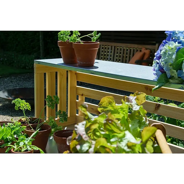 Dobar Pflanztisch Buche - L x B x H: 117 x 62 x 124 cm - Ein Gartentisch mit Holzstruktur und Kräutertöpfen darauf. Die Pflanzen und Blumen auf dem Tisch sorgen für eine natürliche Dekoration im Außenbereich.