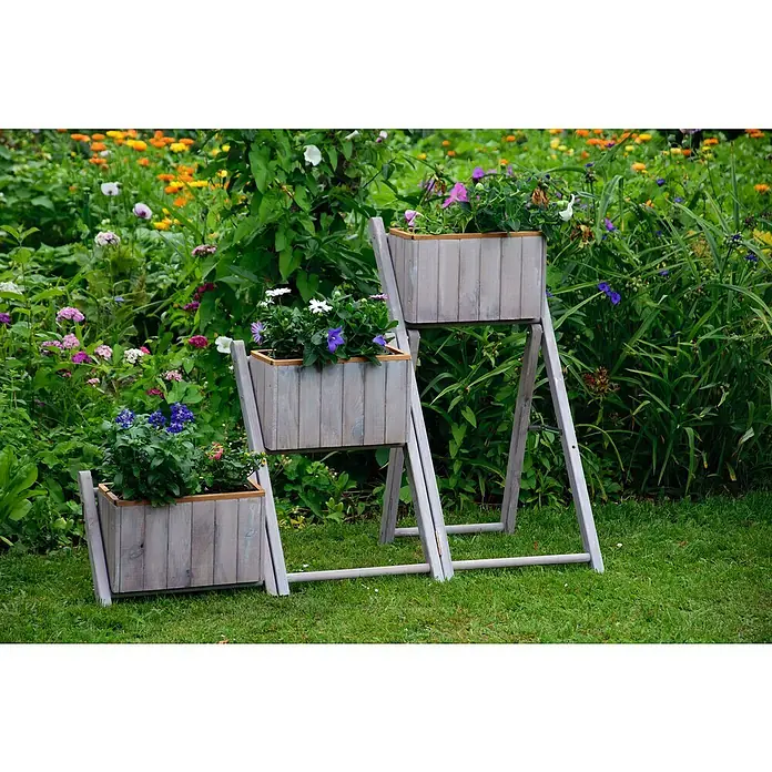 Dobar Pflanzkasten - L x B x H: 41 x 55 x 85 cm, Kunststoff, Grau - Drei hölzerne Pflanzkästen in verschiedenen Höhen, gefüllt mit bunten Blumen, stehen auf einem grünen Rasen vor üppigem Grün.