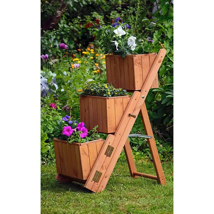 Dobar Pflanzkasten - L x B x H: 41 x 55 x 85 cm, Kunststoff, Braun - Ein dreistufiges Pflanzgefäß aus Holz mit bunten Blumen vor einem grünen Garten.