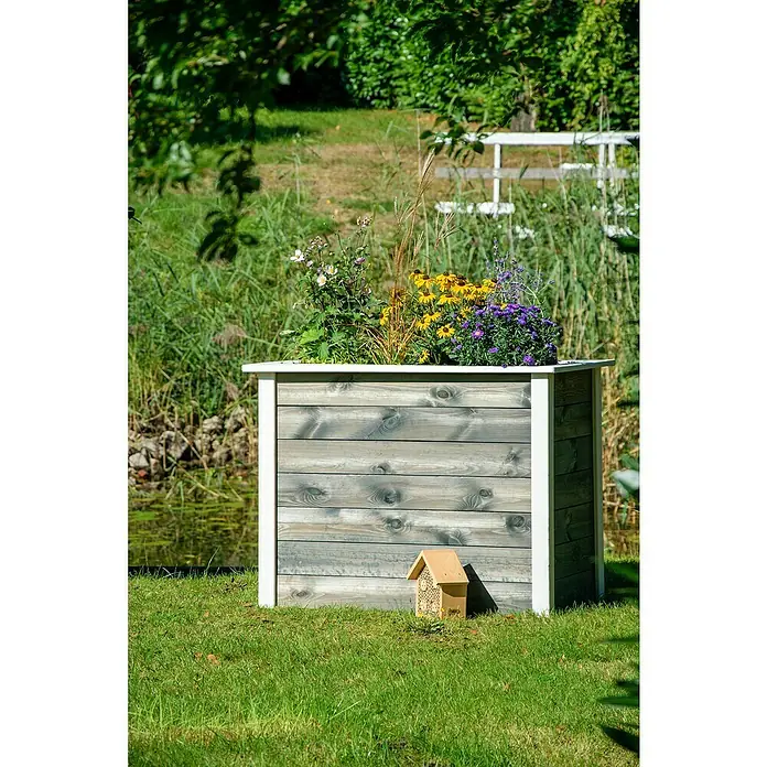 Dobar Hochbeet Two-Tone - L x B x H: 108 x 65 x 80 cm, Holz, Anthrazit/Weiß - Ein bepflanzter Holzkübel mit weißem Rand und einem kleinen Insektenhotel daneben, eingebettet in eine grüne Gartenlandschaft.