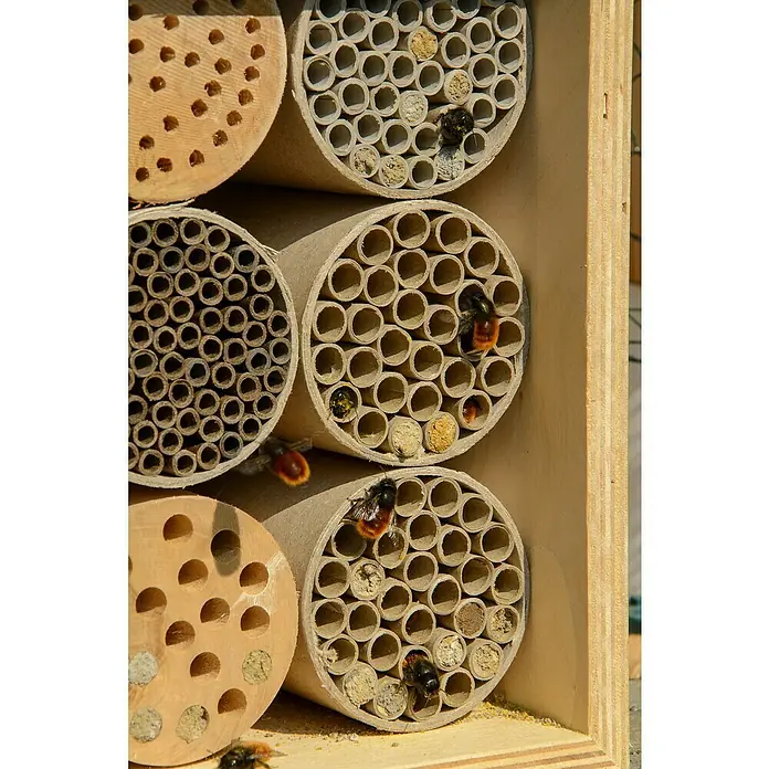 Dobar Insektenhotel - L x B x H: 15 x 12,5 x 22 cm, Braun - Nahaufnahme eines Insektenhotels mit Bienen, die in den Röhren Schutz suchen, perfekt für naturnahe Gärten.
