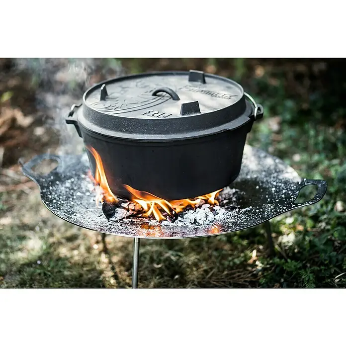 Petromax Dutch Oven - Ø x H: 42 x 20 cm, Gusseisen, 10,8 l, Planer Boden - Ein Dutch Oven aus Gusseisen steht auf einem Outdoor-Kocher über einem Lagerfeuer, ideal für Camping und Outdoor-Küche.