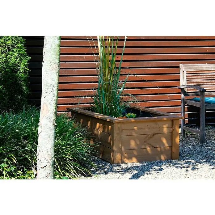 Dobar Hochteich Kubus - L x B x H: 120 x 72 x 42 cm, Braun, 200 l, Holz - Eine hölzerne Pflanzkiste mit hochwachsendem Gras in einem Garten, mit einer Holzbank und einem Holzzaun im Hintergrund.