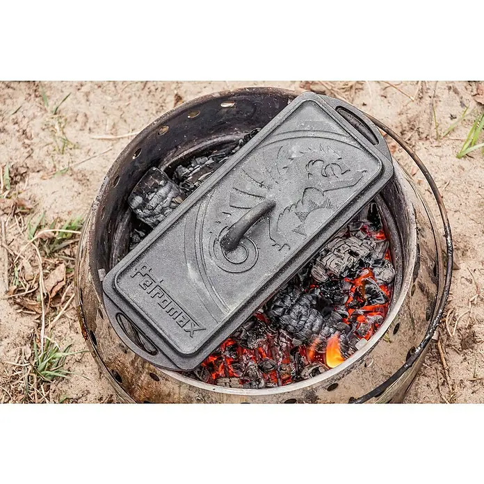 Petromax Auflaufform - L x B x H: 34,5 x 13 x 13,5 cm, Gusseisen, 2,4 l - Ein Petromax Dutch Oven mit Deckel und Kohlen darunter. Ideal für Outdoor-Kochabenteuer und rustikale Gerichte.