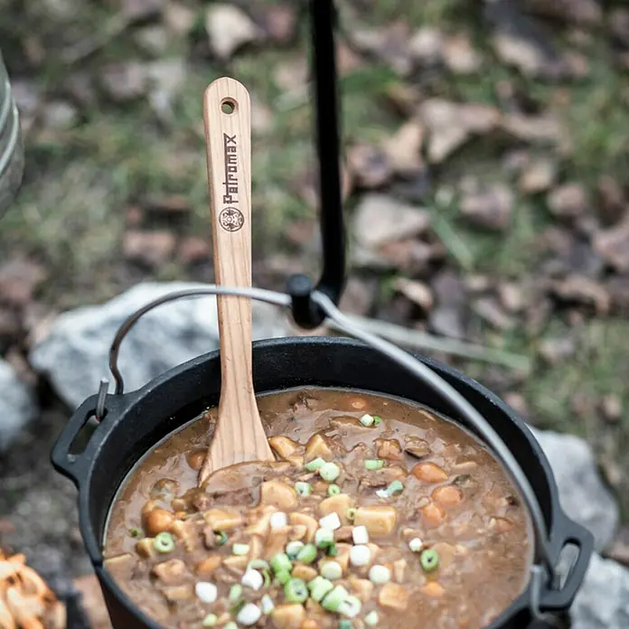 Petromax Holzlöffel - Holz, Braun, 32 cm - Nahaufnahme eines Petromax Dutch Ovens mit einem Holzlöffel darin, der eine herzhafte Mahlzeit umrührt.