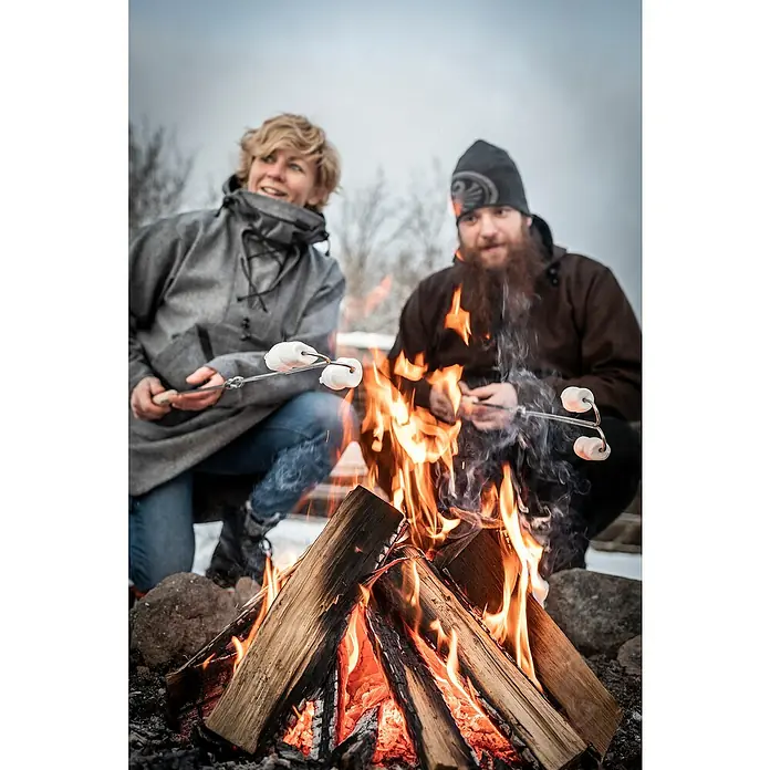 Petromax Grillspieß - Länge: 91 cm, Edelstahl/Buchenholz, Form: Gebogen, 2 Stk. - Bild von zwei Personen, die Marshmallows über einem Lagerfeuer rösten, wobei der Fokus auf den Marshmallows und dem Feuer liegt.