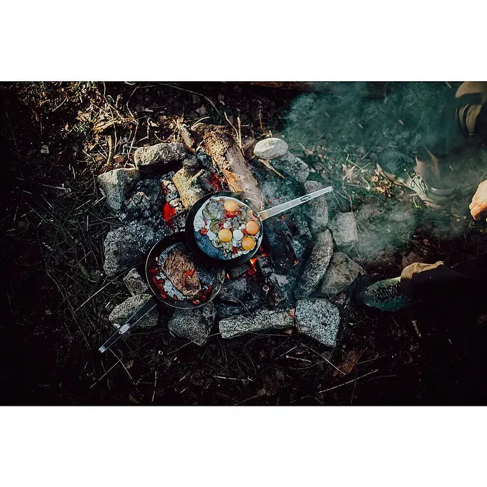 Petromax Grillpfanne - Durchmesser: 24,5 cm - 32 cm, Höhe: 17 cm, Eisen - Zwei Pfannen auf einem Lagerfeuer mit Spiegeleiern und Steak. Camping-Kochgeschirr in der Natur für ein herzhaftes Outdoor-Mahl.