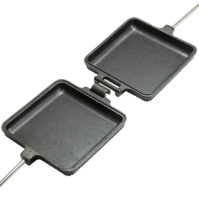 Petromax Sandwicheisen - L x B: 72,5 x 13,5 cm, Gusseisen - Eine offene, gusseiserne Sandwichpresse mit langen Metallgriffen auf einem schwarzen Hintergrund.