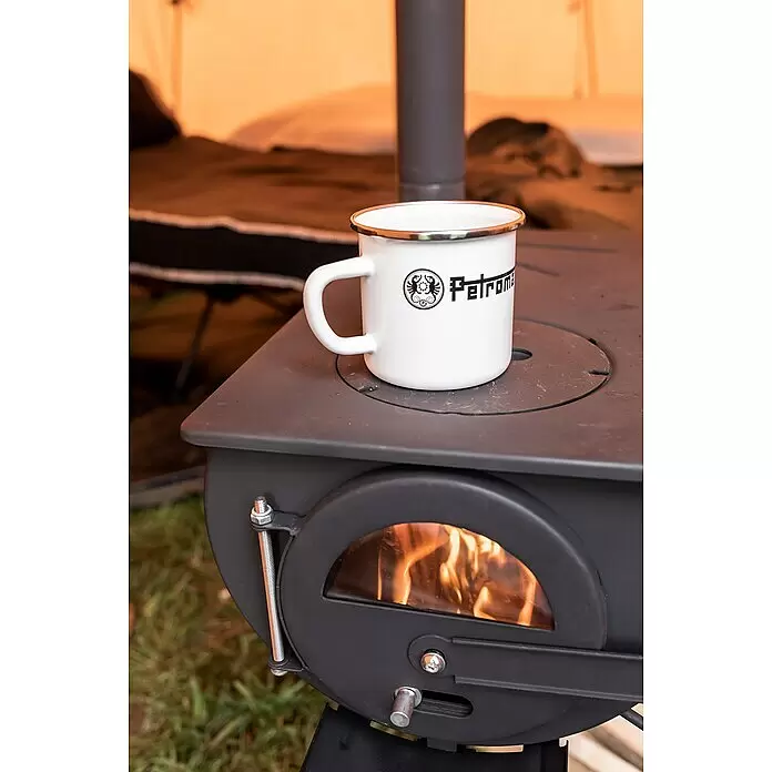 Petromax Tasse - 370 ml, Weiß - Weißer Emaille-Petromax-Becher auf einem schwarzen Campingkocher mit brennendem Feuer, draußen im Zelt.