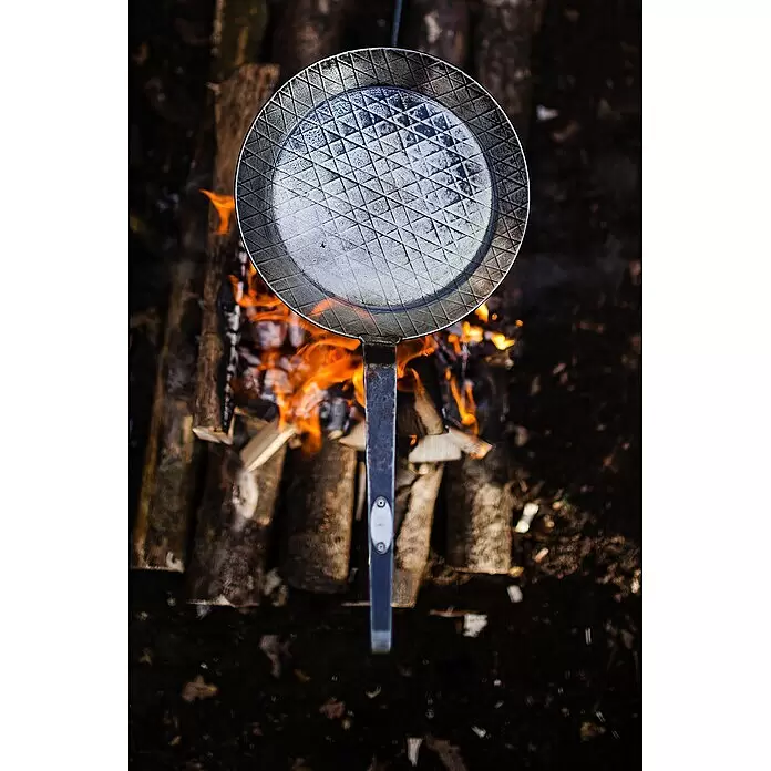 Petromax Grillpfanne - Durchmesser: 20,5 cm - 28 cm, Höhe: 15 cm, Eisen - Metallenes Waffeleisen mit Strukturmuster über einem Lagerfeuer, von oben gesehen.