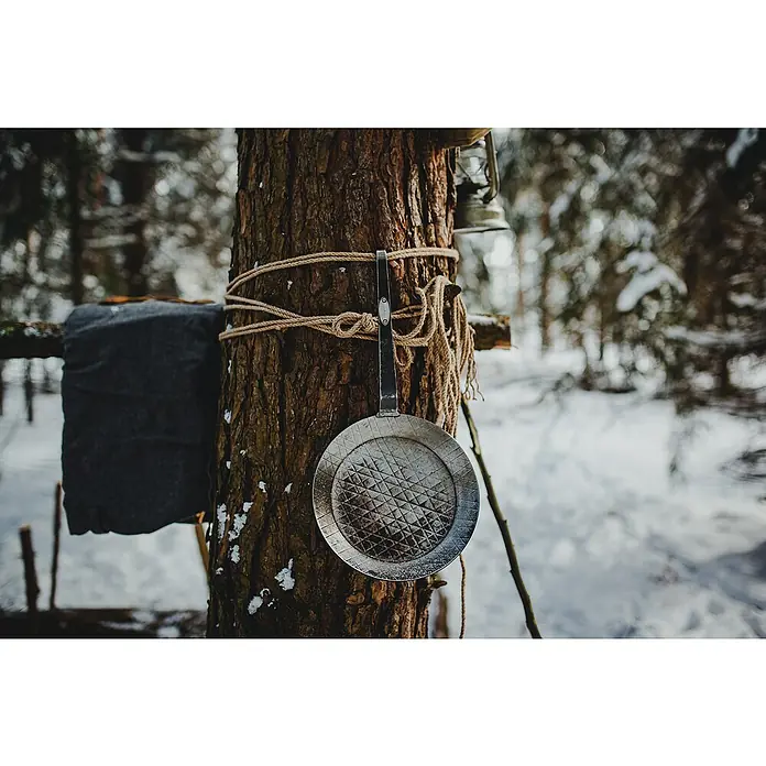 Petromax Grillpfanne - Durchmesser: 20,5 cm - 28 cm, Höhe: 15 cm, Eisen - Nahaufnahme einer Pfanne, die mit Seil an einem Baum befestigt ist, mit einer Laterne darüber, in einer malerischen Winterwaldszene.