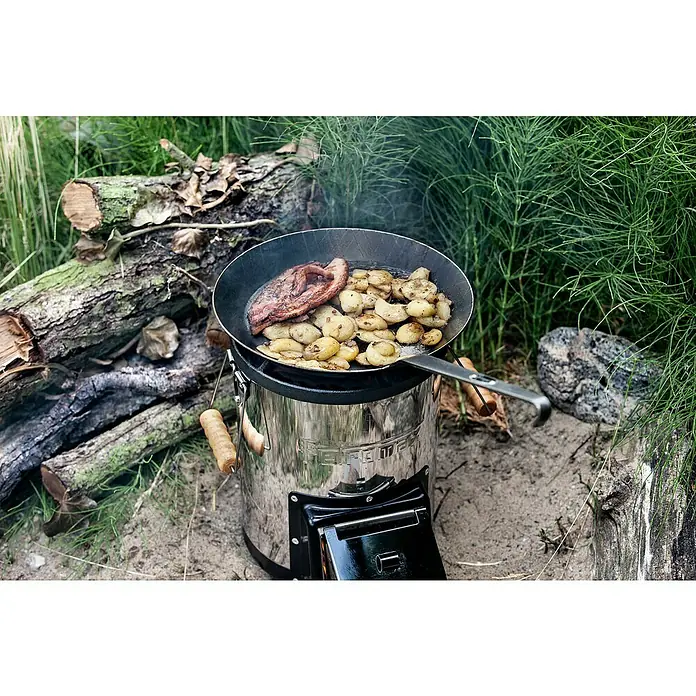 Petromax Grillpfanne - Durchmesser: 20,5 cm - 28 cm, Höhe: 15 cm, Eisen - Zubereitung von Speisen im Freien mit dem Petromax Hobo-Ofen BK1: Fleisch und Kartoffeln werden in einer Bratpfanne über dem Ofen gegart.