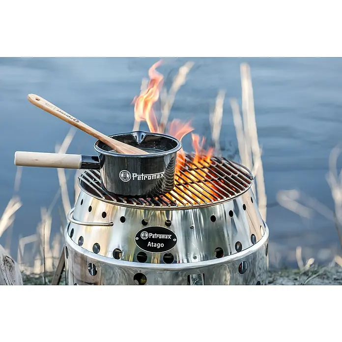 Petromax Kochtopf - Schwarz, Stahl, 1 l, Emailliert - Petromax Atago mit Topf und Kochlöffel beim Kochen über offenem Feuer im Freien, ideal für Camping und Outdoor-Abenteuer.