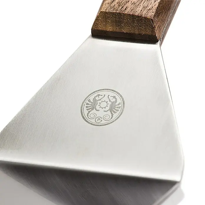 Petromax Grillgutwender - Länge: 29 cm, Edelstahl - Nahaufnahme eines Pfannenwenders mit Holzgriff und eingraviertem Logo auf der Metallfläche.