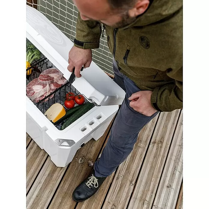 Petromax Einhängekorb - Passend für: Petromax Kühlbox 50 l, L x B x H: 23 x 36 x 14 cm, Schwarz - Mann öffnet weiße Kühlbox mit Fleisch, Gemüse und Käse auf Holzterrasse.