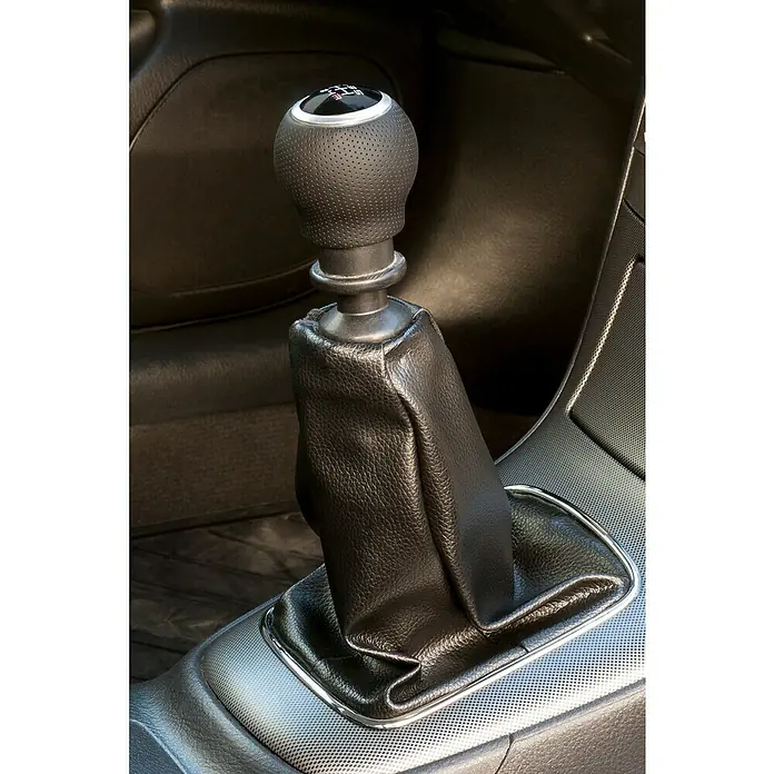 Pomo palanca de cambios OEM - Coches, Negro - Primer plano de un pomo de cambio negro y una funda en el interior de un coche, destacando los controles manuales.